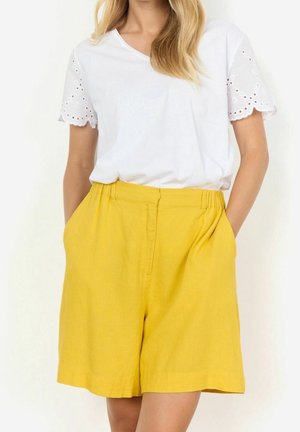 Weißes Baumwoll-T-Shirt mit Ärmeln aus Augenstickerei und gelben Leinen-Shorts mit seitlichen Taschen, flachem Bund und lockerer Passform.