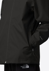 Černá nepromokavá bunda s elegantním designem. Má kapsy na zip, elastické manžety a logo na hrudi a lemu.