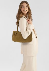 Borsa a spalla in camoscio verde oliva con una texture liscia, forma rettangolare e dettagli cuciti. Presenta due cinturini decorativi sul davanti.