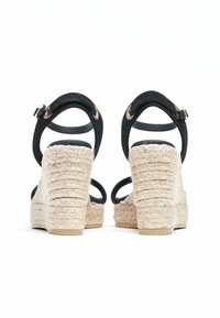 Zwarte espadrille-wedges met bandjes, voorzien van een jute touwhak en gestructureerde stoffen banden, met een gesp-sluiting en een gevoerd voetbed voor comfort.