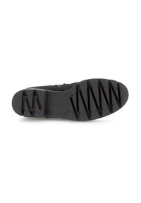 Semelle de chaussure de sport noire avec un motif en caoutchouc texturé, comportant des motifs angulaires et un logo de marque embouti sur le côté.