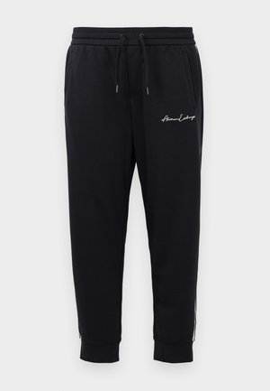 svarte joggebukser laget av mykt stoff med elastisk midje og snøring, med brodert logo og glidelåslommer.