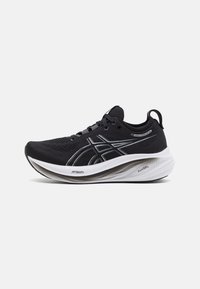 Scarpa atletica nera con tomaia in mesh, suola bianca, ammortizzazione prominente e dettagli riflettenti. Presenta un sistema di lacci e un dettagli di logo.