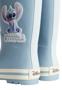 Bottes de pluie en caoutchouc bleues avec des rayures blanches, arborant un graphique du personnage Stitch et le texte "STITCH" sur le côté extérieur. Logo Disney à l'arrière.