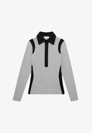 Haut gris à manches longues avec col noir, patte de boutonnage zippée verticale noire et panneaux d'accent noir sur les épaules et les côtés.