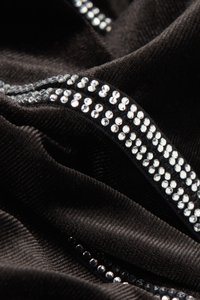 Un tissu noir à la texture douce présente une ligne droite de strass scintillants, rehaussant le design avec des accents brillants.