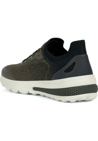 Zapatilla deportiva de color verde oscuro con parte superior de punto texturizado, acentos de goma y una suela blanca que presenta un diseño de agarre en patrón.