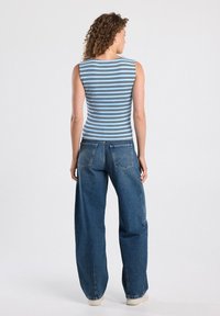 Striped tank top in light blue with dark stripes, paired with loose-fitting blue jeans and light-colored sneakers. Simple design, casual look.