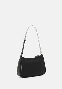 Sac à bandoulière en nylon noir avec une chaîne en métal argenté, comportant une fermeture zippée et un logo embossé sur un côté. Texture lisse et forme incurvée.