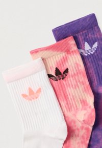 Trīs ribotas apkalpes zeķes baltā, rozā batikas un violetā krāsā, katrai uz aproces ir kontrastējoša Adidas trejlapu logo.
