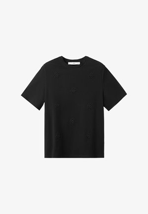 Crna kratka majica s uzorkom reljefnih cvjetnih motiva ravnomjerno raspoređenih sprijeda.