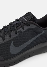 Černá sportovní bota s texturovaným textilním svrškem, bezešvou konstrukcí a výrazným tmavě šedým logem Nike swoosh. Lehká podrážka.