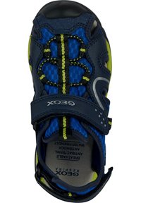 Sandalía infantil cerrada en los dedos de color azul y amarillo con cordones elásticos negros y amarillos y una correa de velcro de la marca "GEOX."