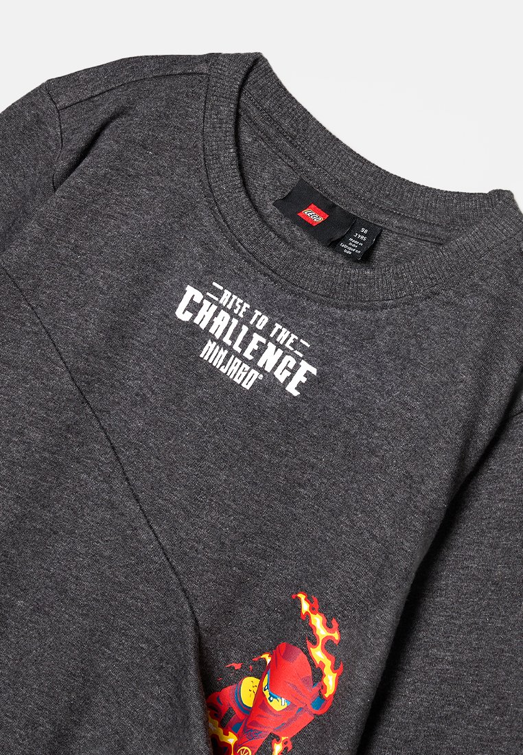 Grauer Sweatshirt mit Rundhalsausschnitt, versehen mit dem weißen Text "RISE TO THE CHALLENGE" und einer bunten Ninja-Grafik auf der unteren linken Seite.