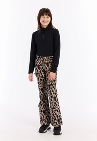 Zwarte lange mouwen zip-up top gecombineerd met bruine leopardprint sneeuwbroeken en zwarte winterlaarzen. De broeken hebben een straight-leg ontwerp.