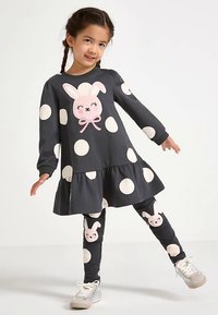 Vestito grigio con pois bianchi, con applicazione di coniglietto rosa; abbinato a leggings con motivi di coniglietti su sfondo scuro.
