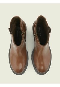 Botas de cuero marrón hasta el tobillo con un acabado suave, cierre de cremallera en el lateral y forro interior texturizado. Suelas de goma negras.