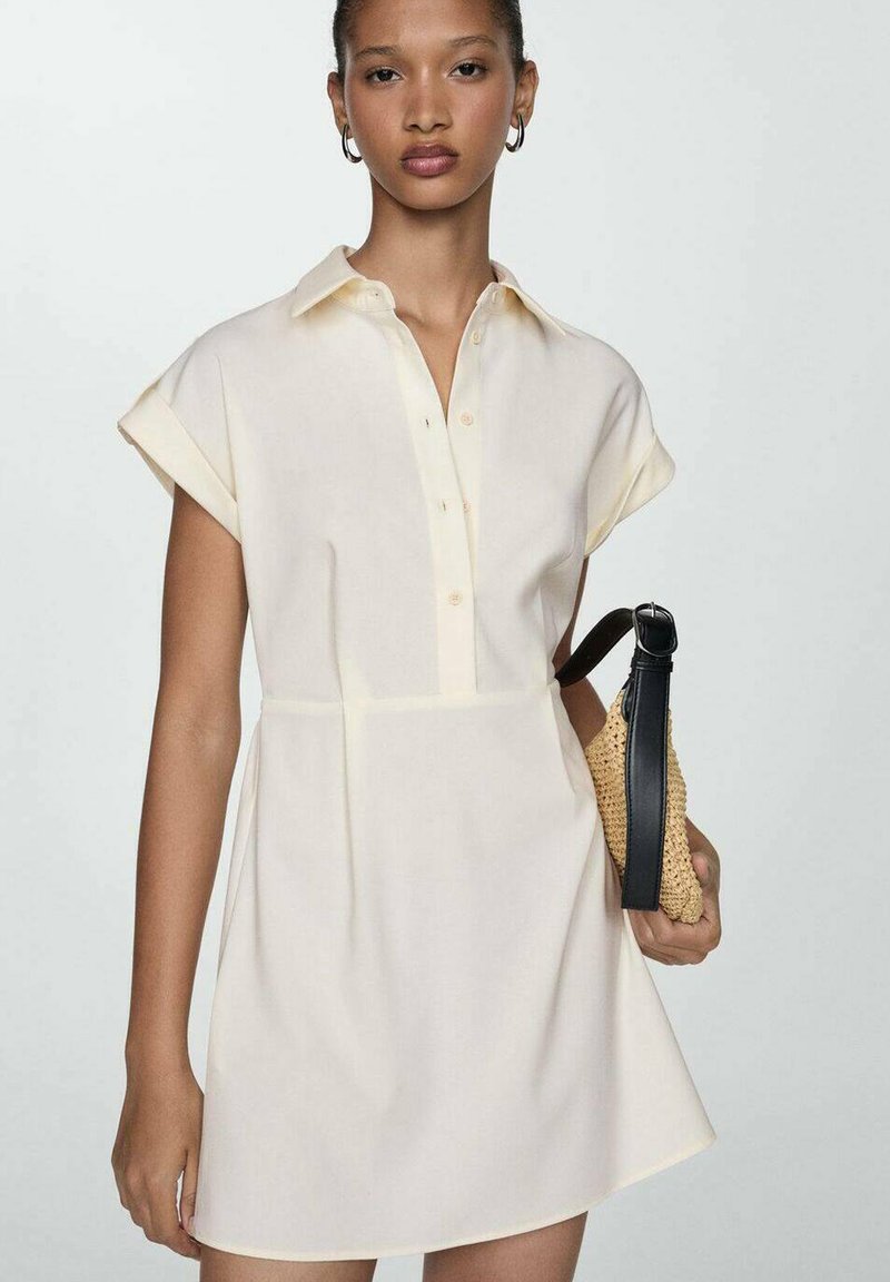 Abito a maniche corte, con colletto in tessuto crema chiaro, con bottoni frontali e vita aderente, abbinato a una borsa intrecciata color beige con tracolle nere.