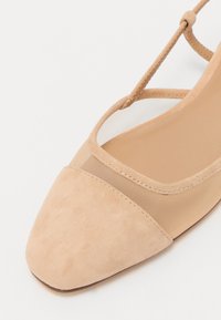 Beige ballerinat kengät, joissa on mokkanahkainen kärki, verkkoyläosa ja ristikkäinen nauhakuosi. Sileä pinta ja terävä kärki.