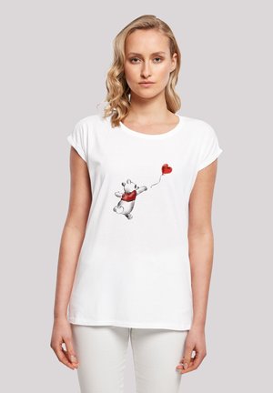 Weißes T-Shirt mit kurzen Ärmeln, auf dem ein grauer und schwarzer Bär einen roten, herzförmigen Luftballon hält, vor einem hellgrauen Hintergrund.
