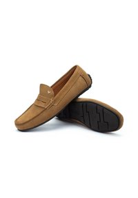 Mocasines de ante en color marrón claro con un diseño de mocasín, que presentan una puntera cosida y una suela de goma negra texturizada para un mejor agarre.