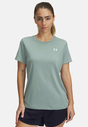 Jasnozielona koszulka sportowa z krótkim rękawem, okrągłym dekoltem i małym białym logo na lewej piersi, zestawiona z ciemnoniebieskimi szortami.