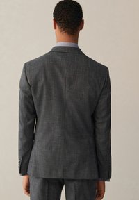 Giacca da suit grigia antracite in tessuto testurizzato, con spacco singolo sul retro, vestibilità aderente, rever a godroni e polsini con bottoni.