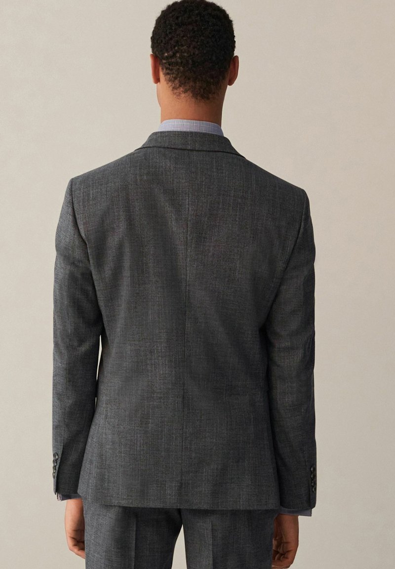 Giacca da suit grigia antracite in tessuto testurizzato, con spacco singolo sul retro, vestibilità aderente, rever a godroni e polsini con bottoni.