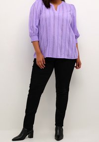 Lavendelblus med v-ringning och puffärmar, med vertikala perforeringar. Matchas med svarta slim fit-jeans och spetsiga svarta stövlar.