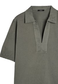 Polo a maniche corte verde oliva realizzato in tessuto morbido, con una delicata ricamo floreale sul colletto e sulle maniche. Design a V.