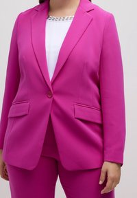 Fuchsia kavaj med en knappstängning, två framfickor och en skräddarsydd passform. Bärs över en vit topp med en pärlbesatt halsringning.