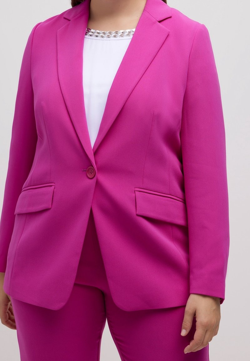 Fuchsia kavaj med en knappstängning, två framfickor och en skräddarsydd passform. Bärs över en vit topp med en pärlbesatt halsringning.