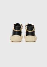 Sorte og kremfargede høye sneakers laget av lær og tekstil, med en teksturert såle og borrelåslukking for justerbar passform.