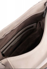 Interno di una borsa in pelle beige con una fodera marrone scuro, caratterizzato da diversi scomparti e una tasca con zip per l'organizzazione.