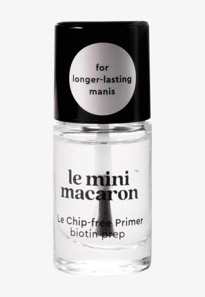 Flacon de primer pour ongles clair étiqueté « le mini macaron », avec un bouchon noir et le texte « pour des manucures plus durables » et « Le primer sans éclats à la biotine, préparation ».