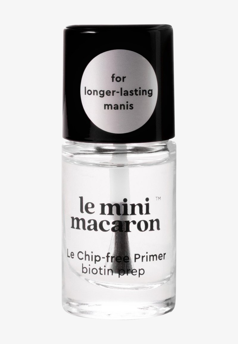 Flacon de primer pour ongles clair étiqueté « le mini macaron », avec un bouchon noir et le texte « pour des manucures plus durables » et « Le primer sans éclats à la biotine, préparation ».