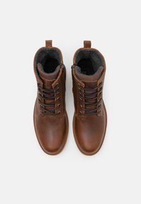 Brown leather ankle boots with a textured finish, featuring a lace-up design, side zipper, and soft gray lining. Round toe and flat sole.