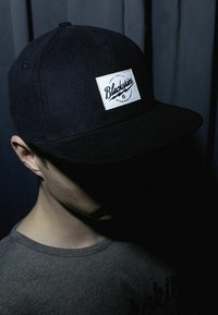 Black corduroy cap features a white patch with "Blackskies" logo. The design includes a flat brim and dark coloring, set against a dark background.