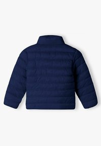 Veste matelassée bleu marine avec col montant, design à losanges horizontal et manches longues. Texture lisse, adaptée aux temps froids.