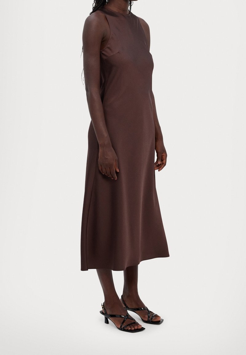 Braunes ärmelloses Midikleid mit hohem Ausschnitt, glatter Textur und A-Linie. Getragen mit schwarzen Riemchenheels.