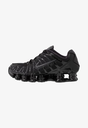 Sapato atlético preto com parte superior em malha e sobreposições brilhantes. Apresenta amortecimento em espiral curvado e linhas texturizadas na lateral. Logotipo da Nike visível.