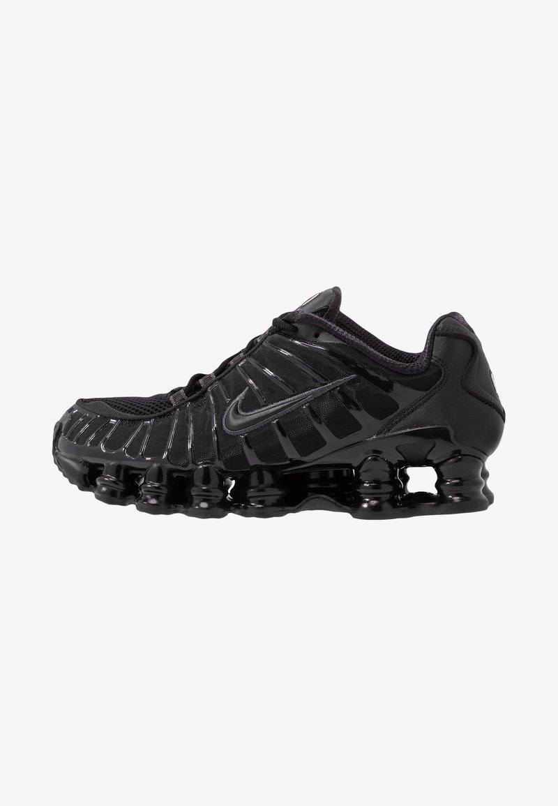 Fekete sportcipő hálós felsőrésszel és fényes részletekkel. Ívelt rugózó párnázással és texturált vonalakkal rendelkezik az oldalán. Nike logó látható.