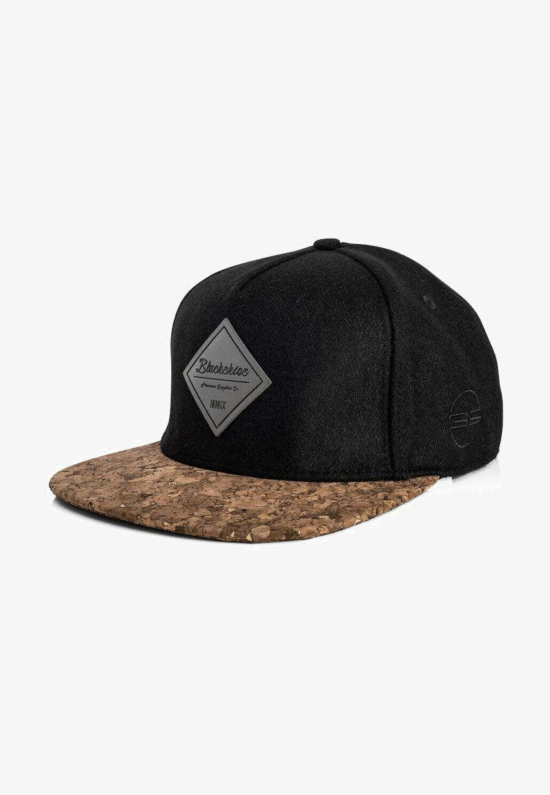 Cappello nero con visiera in sughero, caratterizzato da un'etichetta logo a forma di diamante grigia. Tessuto morbido e testurizzato con design piatto.