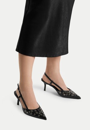 Czarne sandały na obcasie z odkrytymi piętami i szpiczastymi noskami, ozdobione metalowymi oczkami oraz cienkimi obcasami. Wykonane z gładkiego materiału o eleganckim designie.