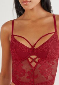 Bordeaux blonde bodysuit med blomstermønstre, undertråg og justerbare stropper med et krydset design og hægte-lukning.