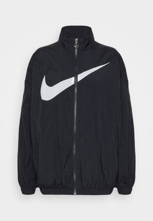 Černá bunda vyrobená z lehkého materiálu, s vysokým límcem, plným zipem a velkým bílým logem Nike swoosh na přední straně.