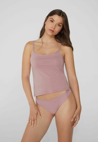 Helles rosa Tanktop mit dünnen Trägern und relaxed Fit, kombiniert mit passenden, taillierten Bikinihosen, beide aus weichem Material gefertigt.