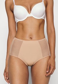 Beige hochgeschnittene Unterwäsche mit Netzeinsätzen an den Seiten und glattem Stoff. Sie verfügt über ein nahtloses Design und einen elastischen Bund für hohen Tragekomfort.