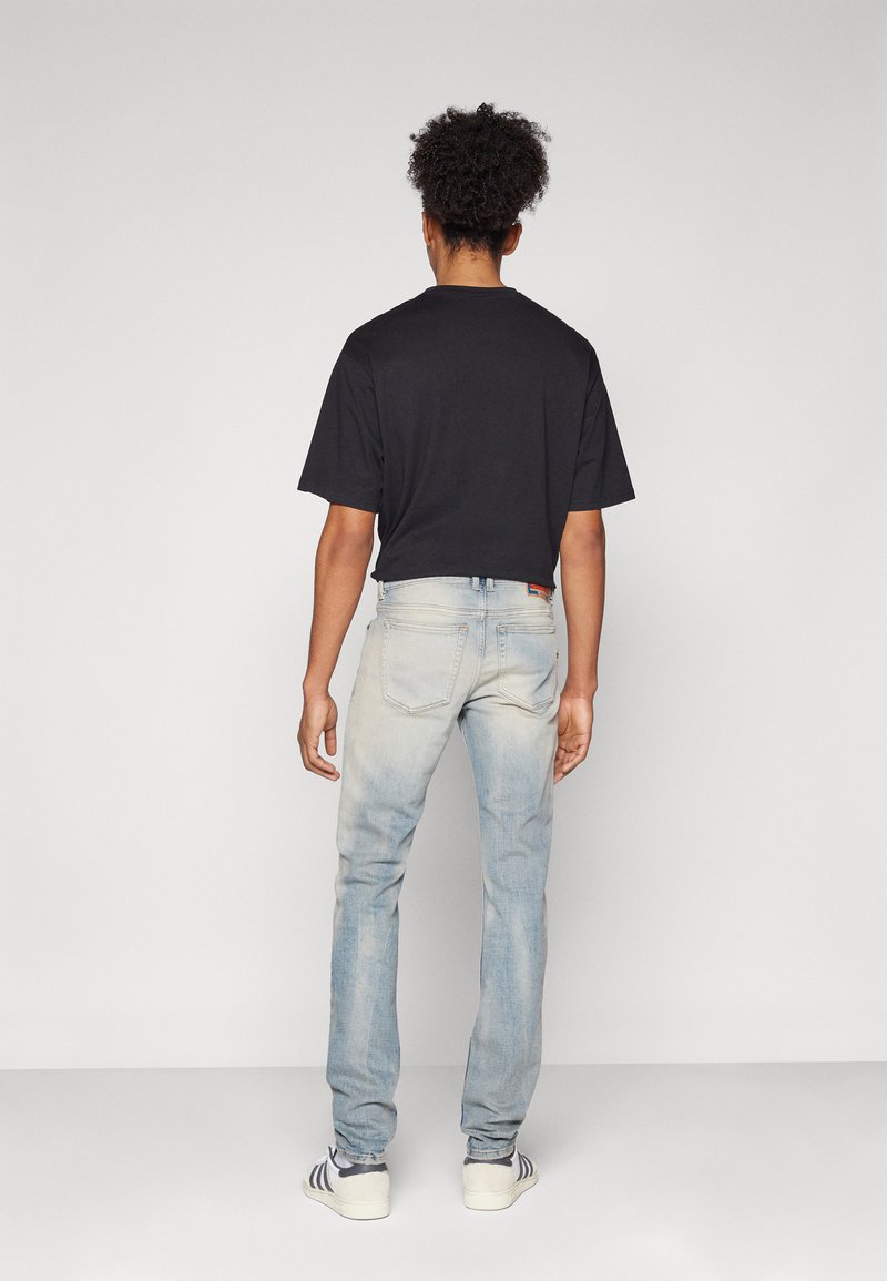 Zwart cropped t-shirt met korte mouwen, gecombineerd met lichtblauwe vervaagde jeans en witte sneakers met marineblauwe strepen. Zichtbare stiksels.