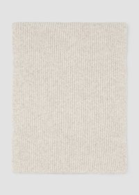 Beige gebreide deken met een geribbelde textuur; bevat kleine, subtiele decoratieve elementen. Rechthoekige vorm, zacht materiaal.